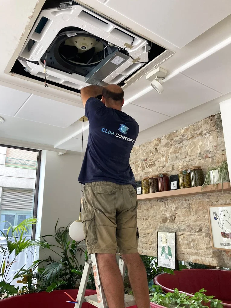 Technicien ClimConfort en pleine installation d'une unité de climatisation